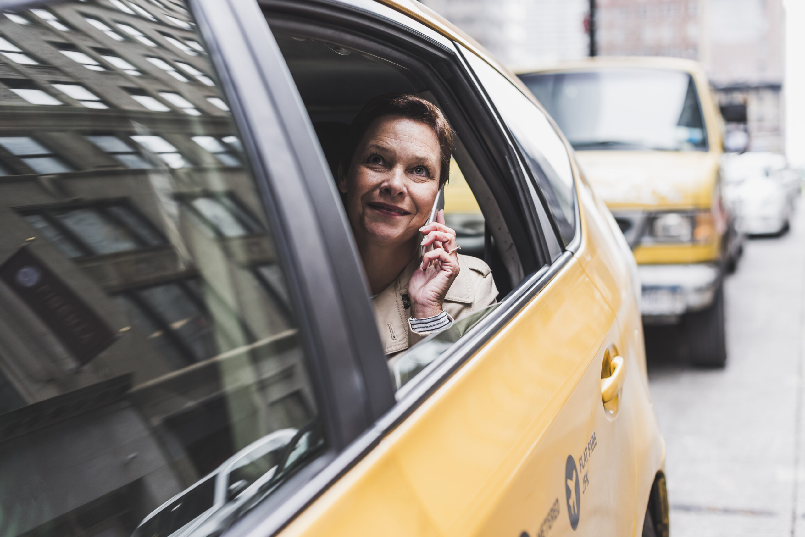 USA, New York City, smiling woman in taxi on cell phone